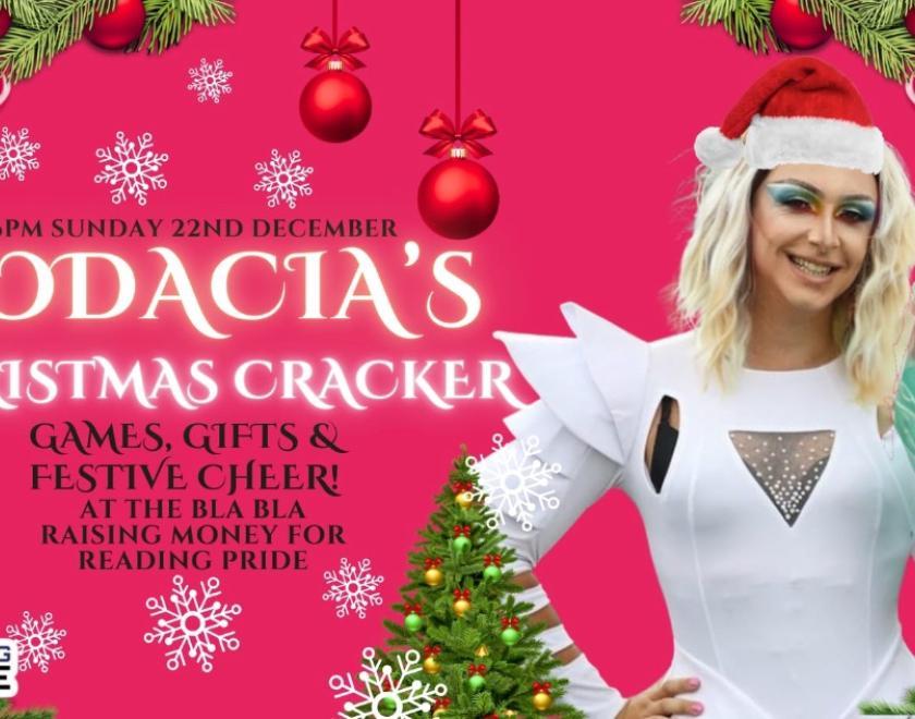 drag queen in a white outfit and Christmas hat on a pink background