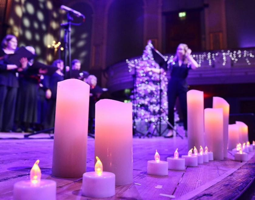 Candles on stage in Reading Concer Hall, with a choir out-of-focus in the background