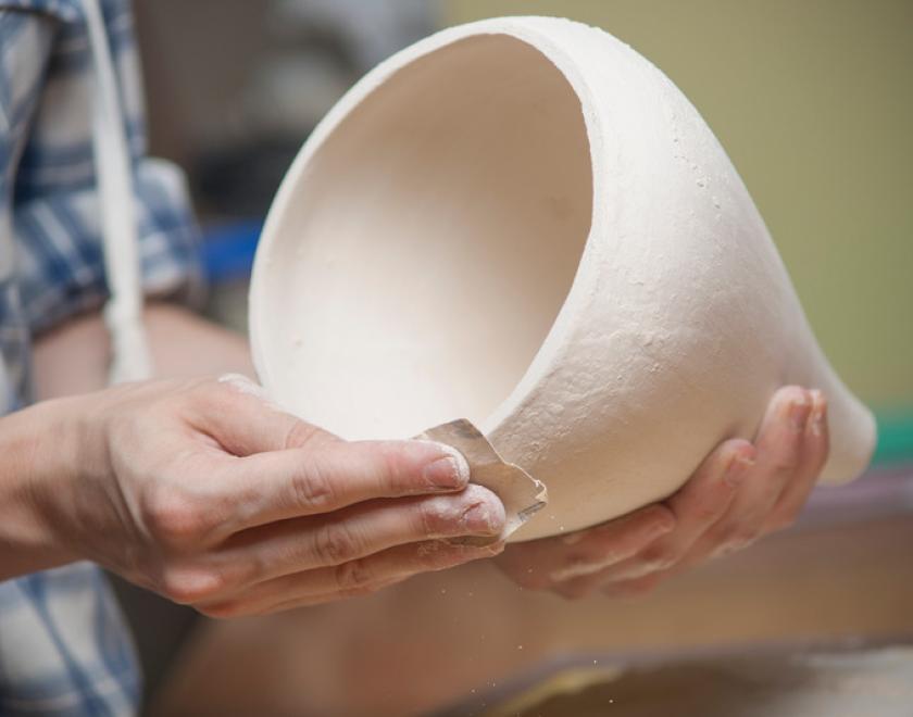 Hands shaping a ceramic pot
