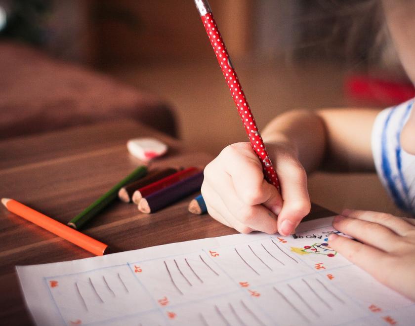 Image of child drawing with a pencil.