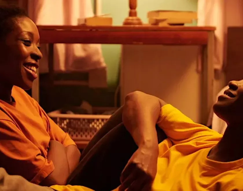 Screenshot from the film Dreamers with two black women smiling and sitting together
