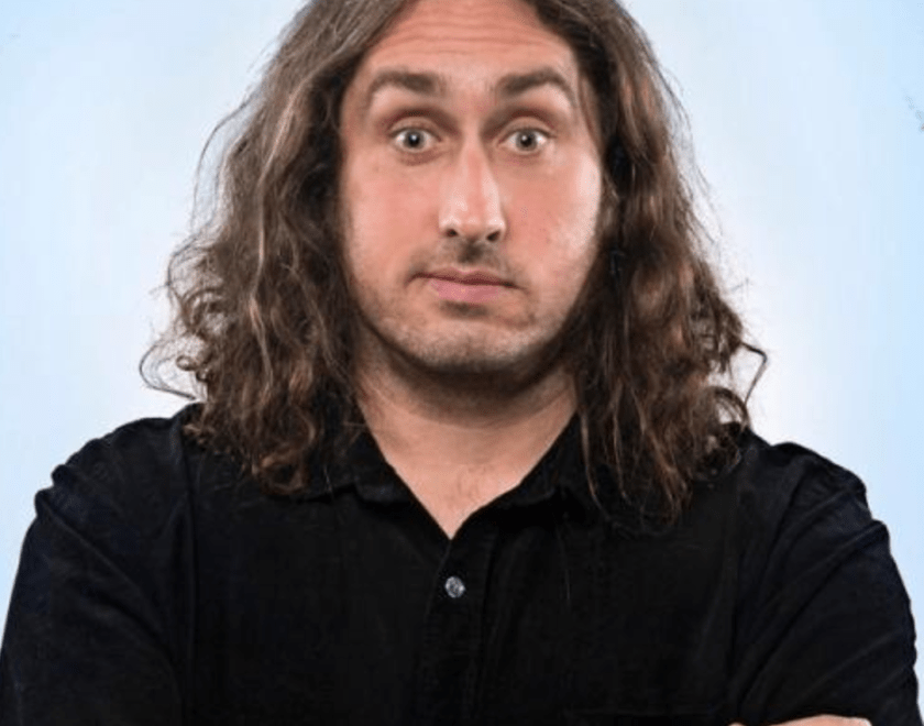 Ross Noble - man with long hair on blue background 