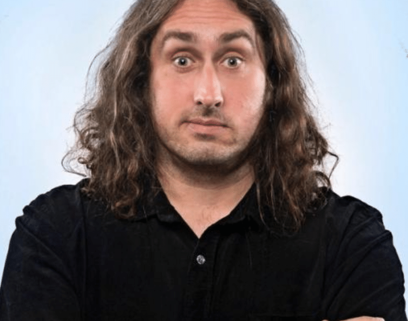 Ross Noble - man with long hair on blue background 