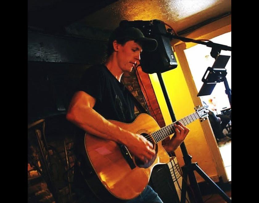 Singer Harry J playing an acoustic guitar in a pub