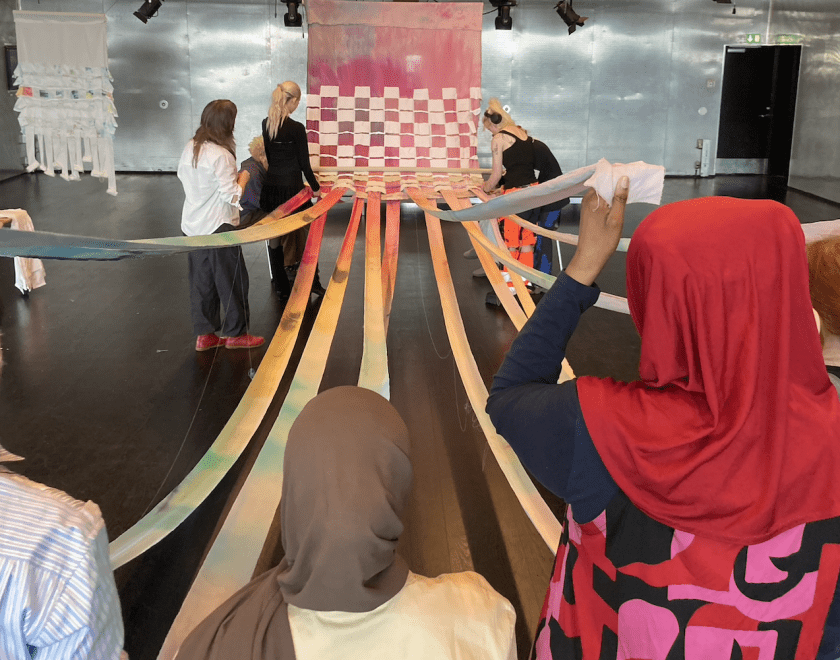 large woven material with people holding the fabric 