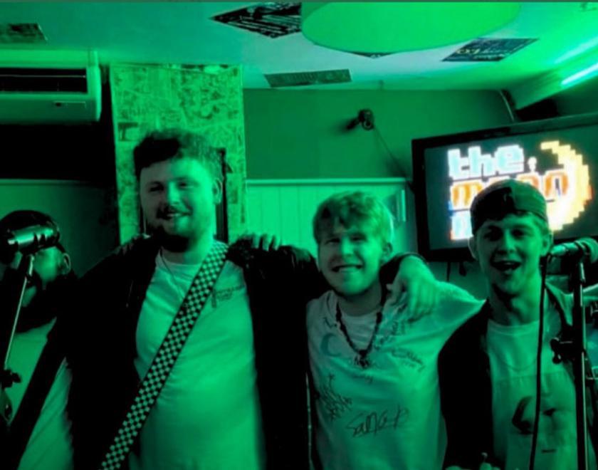 Green monochrome photo of four 20-something lads lined up in a pub