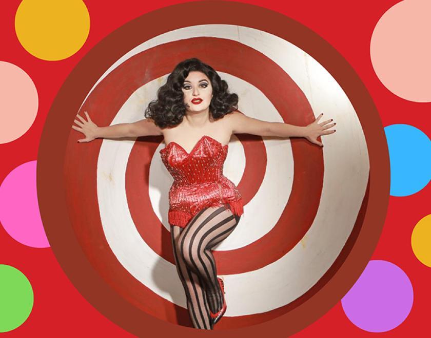 Drag Queen ZeeZee Stardust in a red corset against a polka-dot background