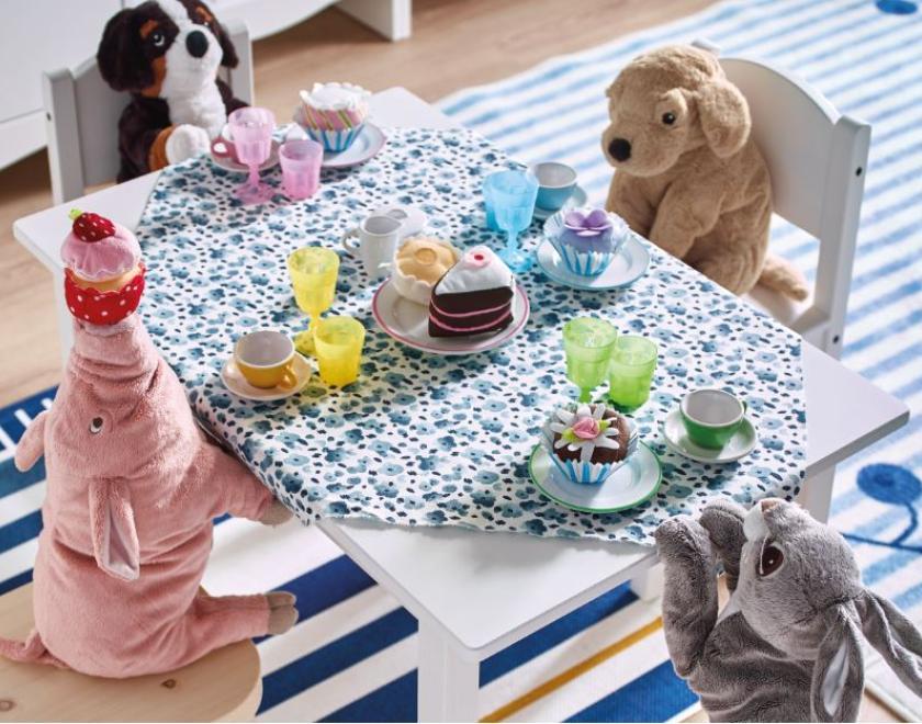 Stuffed toys sat around a childrens table having a tea party