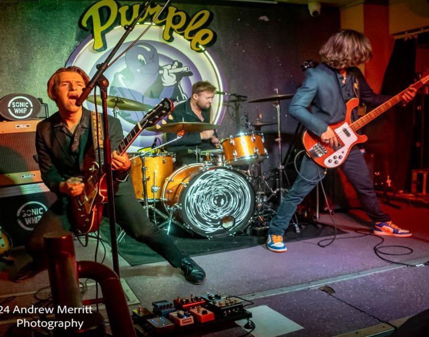 three piece band performing on stage at the Purple Turtle