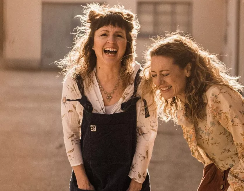 Two women in dungarees laughing