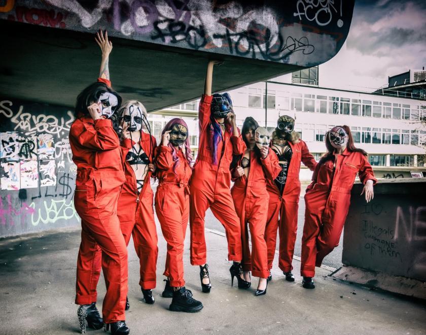 Women in Slipknot-style orange jumpsuits and horror masks, some with sexy burlesque outfits peeking out