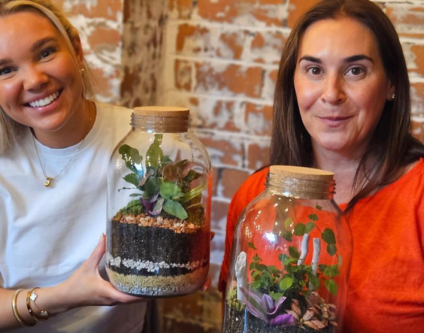Two women smiling and holding terrariums
