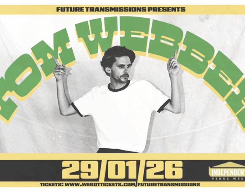 Tom Webber posing in a white t-shirt and black trousers