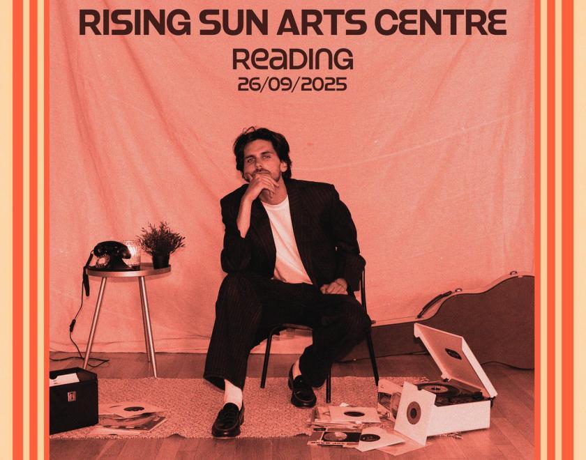 Tom Webber gig poster featuring Tom wearing a black suit with white t-shirt sitting amongst a vintage record player and a guitar case