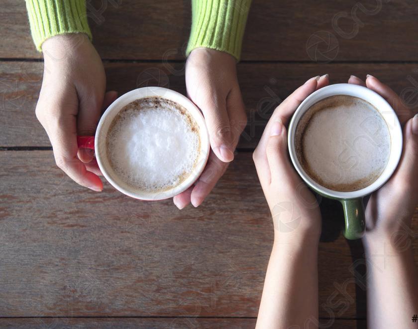 Image of hands of two people holding coffee cups.