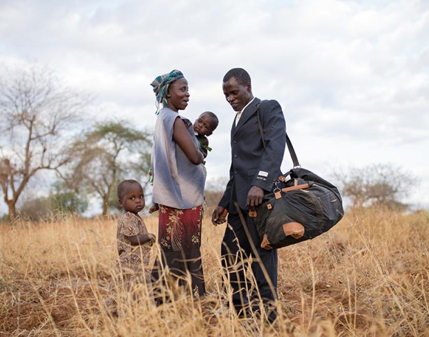 Still from the film "Thank You For The Rain" featuring an African family standing in the yellow grass of their homeland