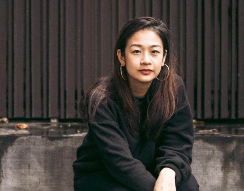 Aly Koh is a young Singaporean woman, sitting on a grey sofa.