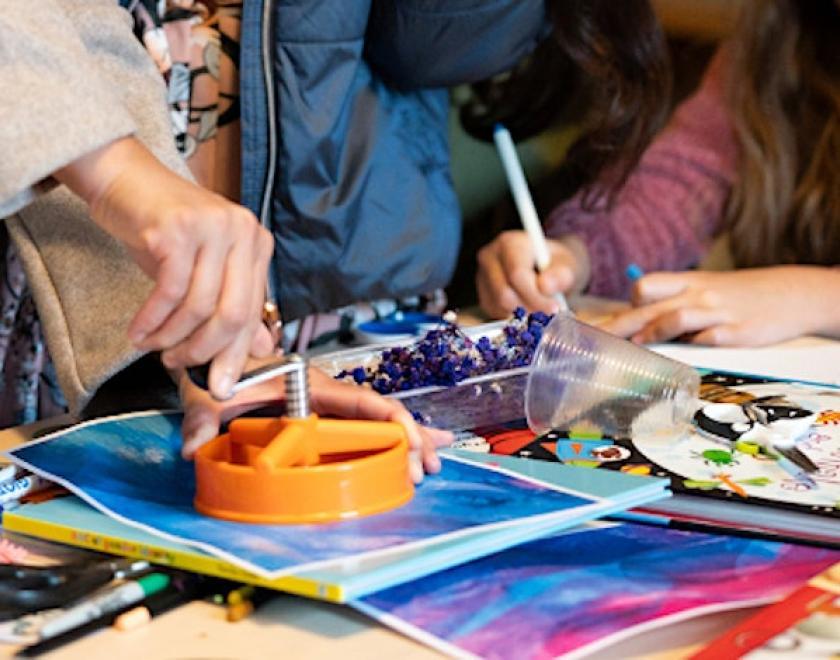 people creating art in a workshop, seen in close up with their hands on the table