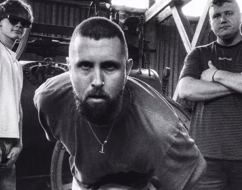 Musicians Wilswood Buoys, three white men standing in front of some industrial equipment