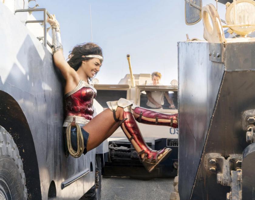 Image of Wonder Woman squeezing between two moving vehicles